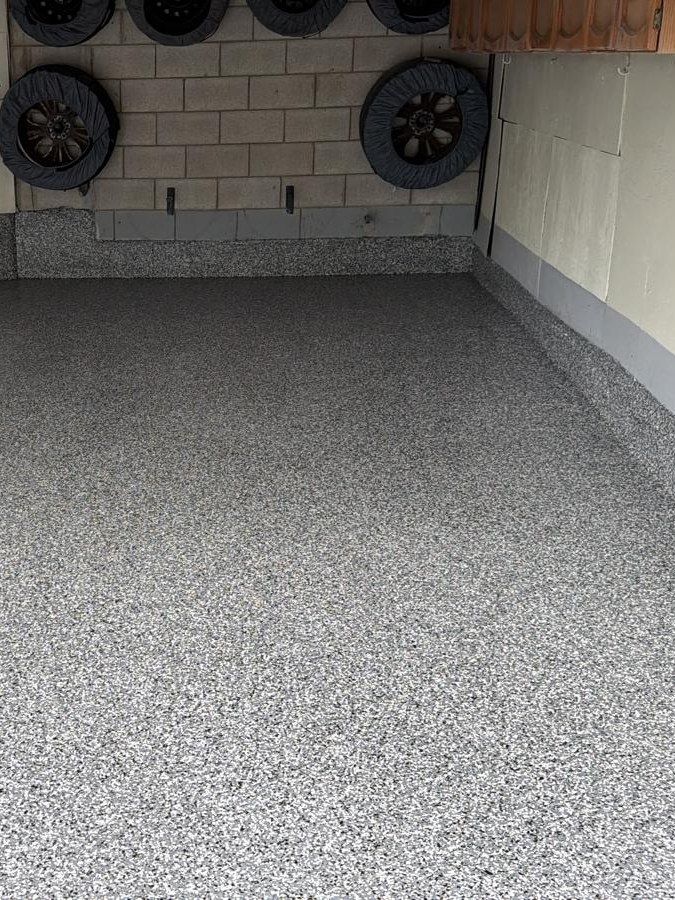 Garage with a grey and white flake floor coating that runs up the base of the walls